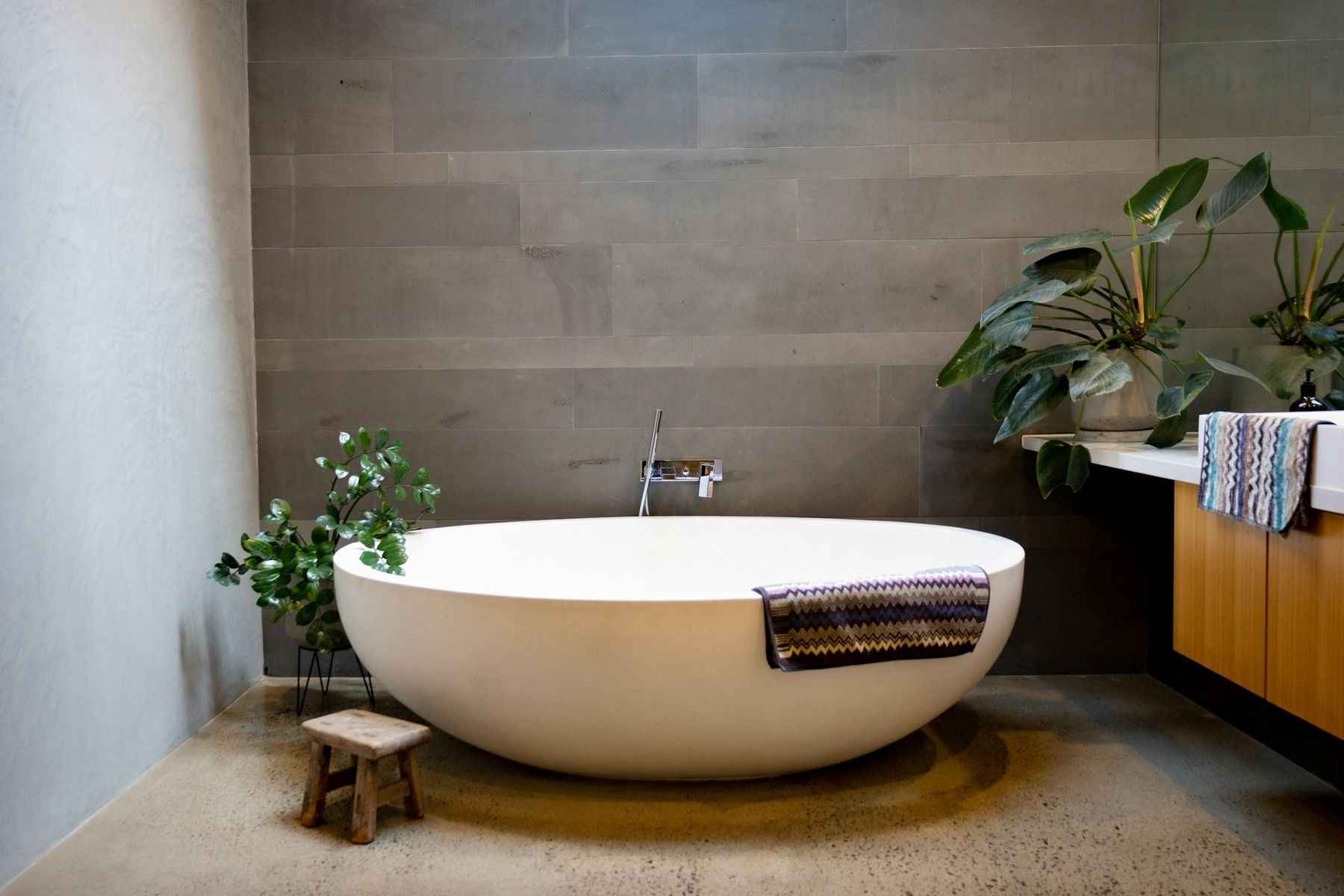 Bathroom with a seamless trowelled wall and polished concrete floor around a stone bath